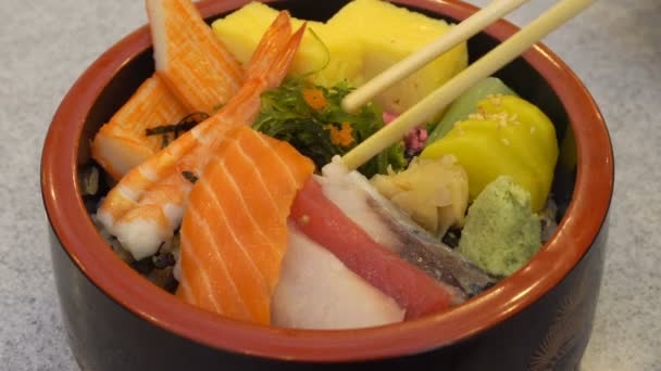 在日本传统碗中用筷子将新鲜的未煮熟的鲑鱼和鸡蛋与芥末和蔬菜放在木桌上通过运动 — 图库视频影像