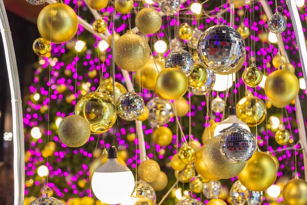 Pembe bokeh ile Noel ağacı gece zamanında asılı altın Noel top