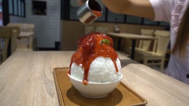 Bingsu, kesilmiş buz ile biraz süt krem krem peynir ve taze çilek ile tepesinde. Kadın el çilek yığını. Ağır çekim 120p