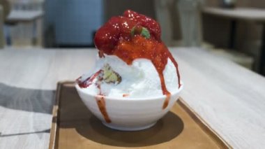 Zaman atlamalı Bingsu, kesilmiş buz ile biraz süt krem krem peynir ve taze çilek ile tepesinde. Kadın el çilek yığını. 