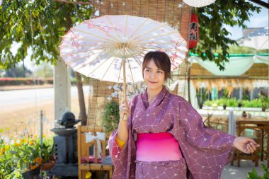 Kız geleneksel pembe yukata giyiyor. Japonya 'nın ulusal elbisesi ve şemsiyesi.