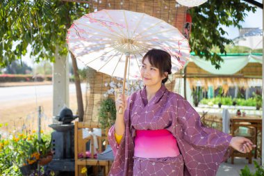 Kız geleneksel pembe yukata giyiyor. Japonya 'nın ulusal elbisesi ve şemsiyesi.