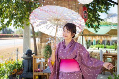 Kız geleneksel pembe yukata giyiyor. Japonya 'nın ulusal elbisesi ve şemsiyesi.