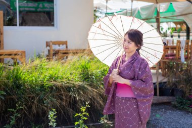 Kız geleneksel pembe yukata giyiyor. Japonya 'nın ulusal elbisesi ve şemsiyesi.