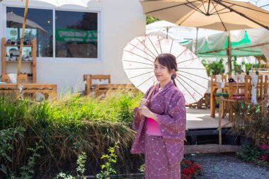 Kız geleneksel pembe yukata giyiyor. Japonya 'nın ulusal elbisesi ve şemsiyesi.