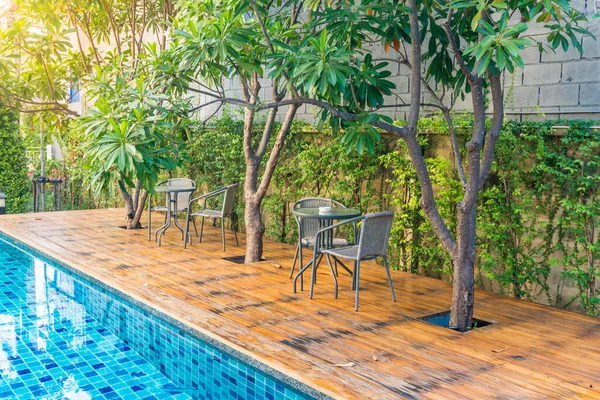 Swimming pool at hotel with decorated with trees and chairs for relaxing