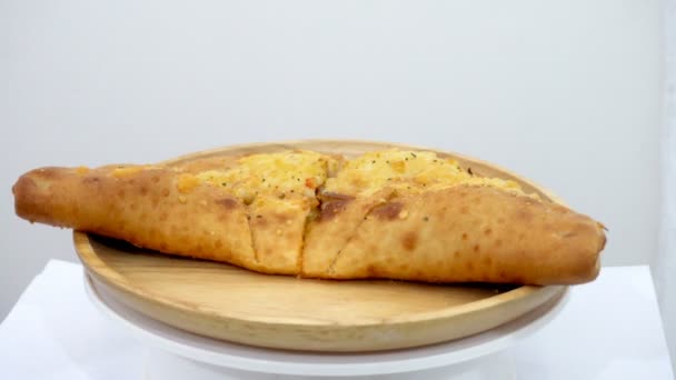 Pizza puff is rotating on a wooden plate with a white background — Stock Footage Pizza Puff Rotating Wooden Plate White Background Video Clip