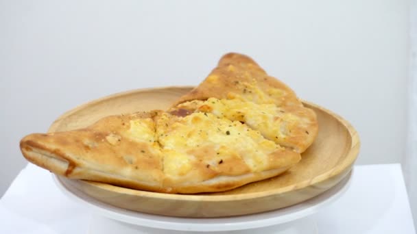 Pizza puff is rotating on a wooden plate with a white background — Stock Footage Pizza Puff Rotating Wooden Plate White Background Royalty Free Stock Footage