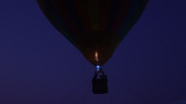 Propan gazı yangın ocağını renkli sıcak hava balonlarıyla yakın çekim yapın. Gece vakti yerin üstünde uçun.