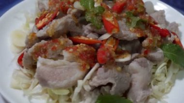 Pork Lemon (Moo Ma-nao) nane yaprağı ve baharatlı Tayland yemeği tarzında beyaz bir tabakta..