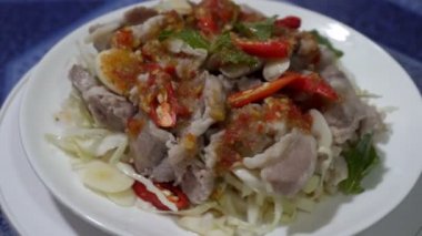 Pork Lemon (Moo Ma-nao) nane yaprağı ve baharatlı Tayland yemeği tarzında beyaz bir tabakta..
