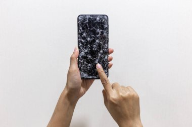 Beyaz arka planda kırık ya da çatlak ekranlı akıllı telefonu tutan kadın elleri. Kullanılamaz, internetten alışveriş yapılamaz ve iş konsepti yapılamaz. Odaklanmayı seç