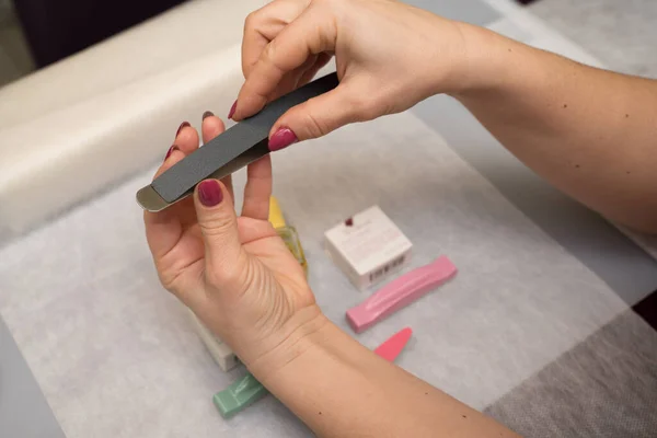 Woman hands in a nail salon receiving a manicure. Nail filing. Close up, selective focus.