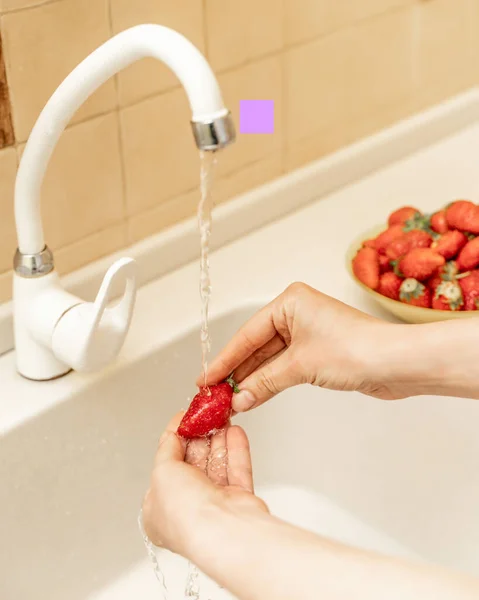 女人们的手把草莓和蓝莓放在厨房水池里的水里洗 有选择的重点 吃水果前要先洗净 — 图库照片