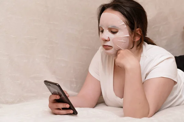 Mladá Žena Masce Kosmetické Látky Leží Pohovce Bílém Tričku Surfuje — Stock fotografie