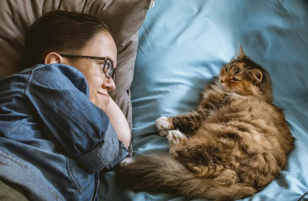 Teenager Brýlích Džínové Košili Kočka Sebe Dívají Zatímco Leží Modrém — Stock fotografie