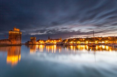 Fransız şehrinin rıhtımında güneş batıyor ve gemiler bağlı.