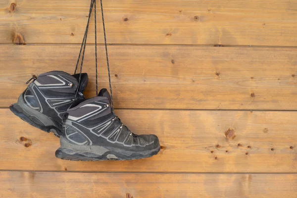 Hiking boots hanging on a wooden wall.