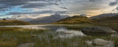 Ön planda florlar ve Fransız Alpleri 'nin arka planında Croix de Fer dağlarıyla manzara.