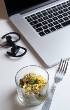 Çatallı, kulaklıklı kuskus ve arka planda dizüstü bilgisayar..