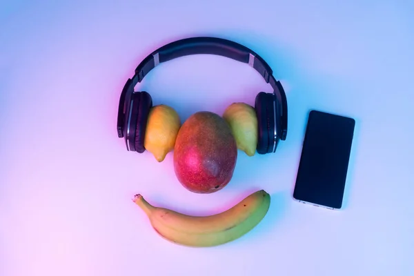 Fruit and vegetables listening to music with phone and disco lights.