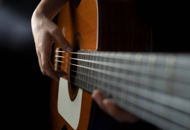 Siyah arka planda gitar çalan kişi