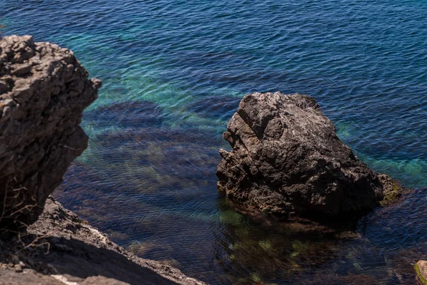 Un gran acantilado de piedra está situado en las aguas del mar negro cerca de la orilla. La vista desde arriba — Foto de Stock