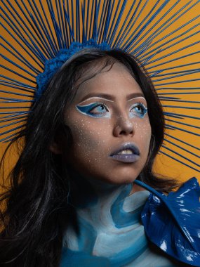 İlham perisi vücut resmi yapıyor sarı fotoğraf stüdyosu arka planında ve farklı ışıklarla oynuyor ve poz veriyor.