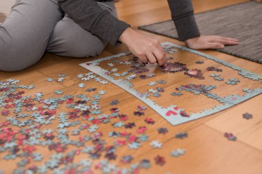 Anne ve kızı, Cornavirus covid-19 yüzünden evin zemininde bir yapbozla oynuyorlar.