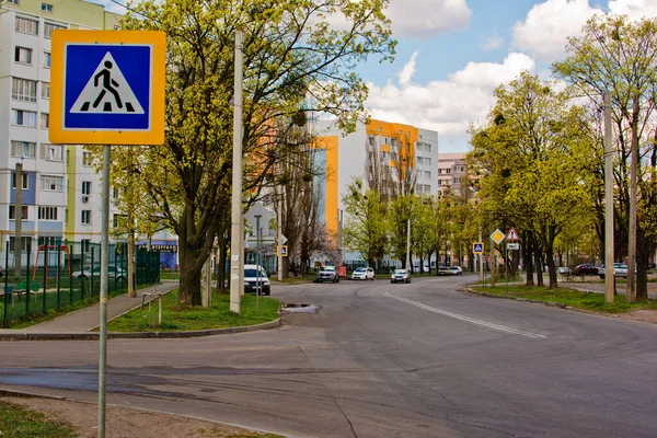 Akşamları ağaçlar ve evler arasında trafik işaretleriyle cadde boyunca giden arabalar