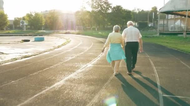 Äldre par promenader längs löparbanan — Stockvideo