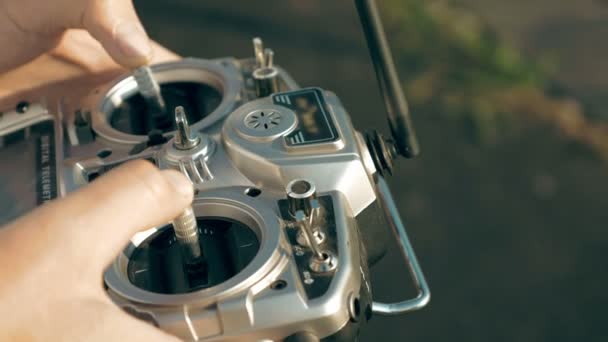 Manos sosteniendo un transmisor que controla el dron FPV — Vídeo de stock