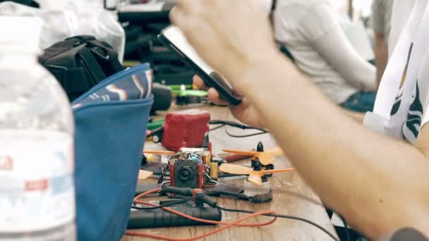 Man using smartphone while assembling FPV drone — Stock Video
