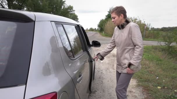 Женщина садится в машину — стоковое видео