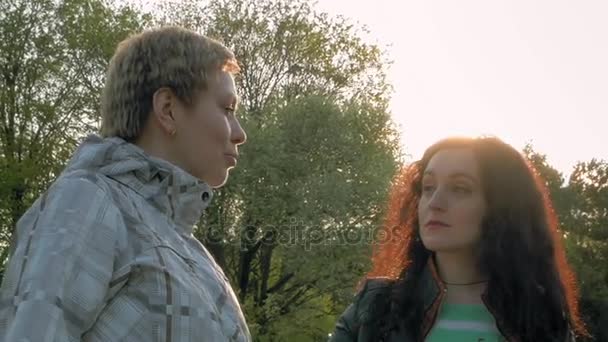 Dva přátelé dívky smajlík mluví v zeleném parku — Stock video