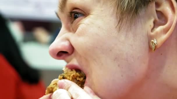 Молодая женщина ест фаст-фуд в кафе-ресторане — стоковое видео