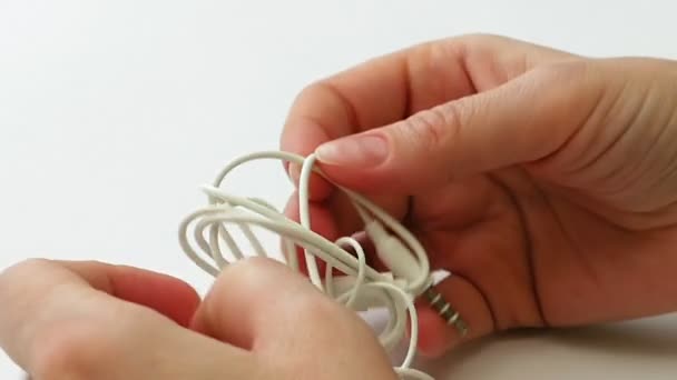 Mujer desenreda auriculares enredados o nudo auricular — Vídeos de Stock