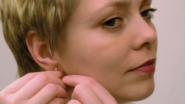 Jolie femme blonde porte des boucles d'oreilles et se montre intelligente — Video