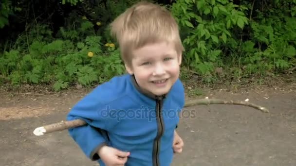 Menino feliz brinca com vara ri e sorri — Vídeo de Stock