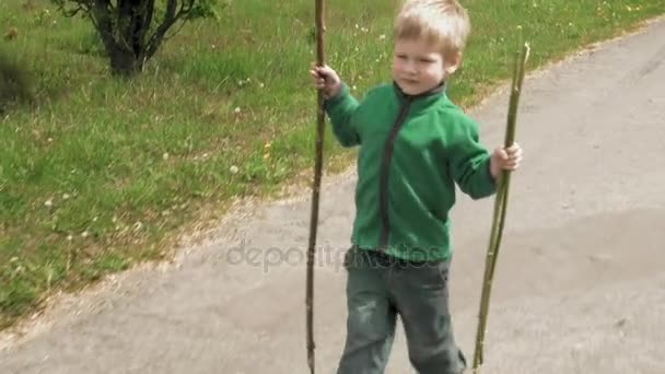 Glücklicher kleiner Junge spielt mit Rute Spaziergänge im Freien Straße — Stockvideo