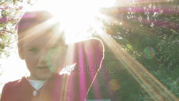 Pretty little girl in red dress behind the sun — Stock Video