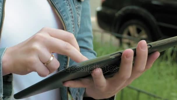 Vrouw soorten teksten op de tablet pc lopen buiten — Stockvideo