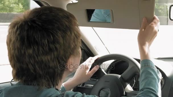 Mujer corrige el maquillaje en un espejo de la visera del sol del coche — Vídeo de stock