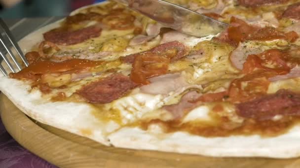 Cortar una pizza con la ayuda de un tenedor y un cuchillo — Vídeos de Stock