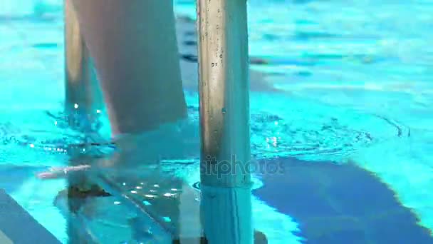 Žena jde dolů po schodech do vody bazénu — Stock video