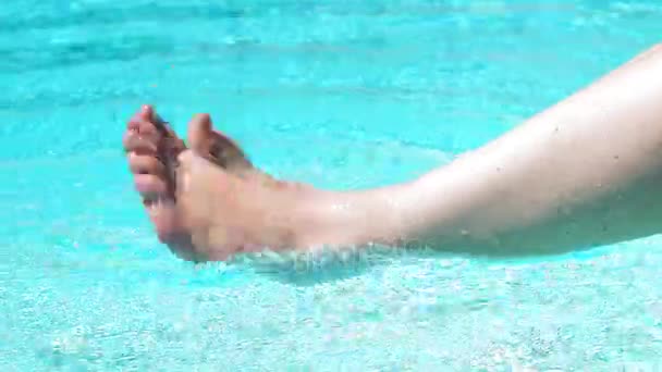 En kvinna flyttar benen i vatten poolen — Stockvideo