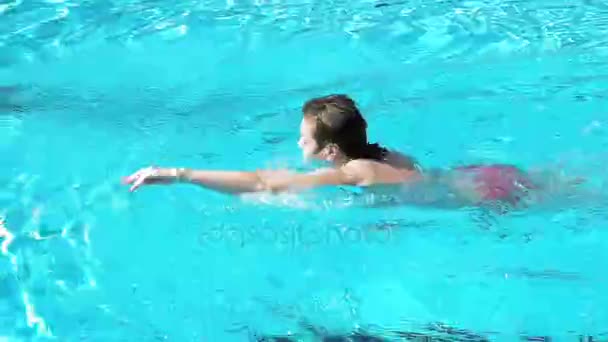 Mulher está nadando em uma piscina em um dia de verão brilhante — Vídeo de Stock