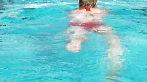 Frau schwimmt an einem hellen Sommertag in einem Pool — Stockvideo