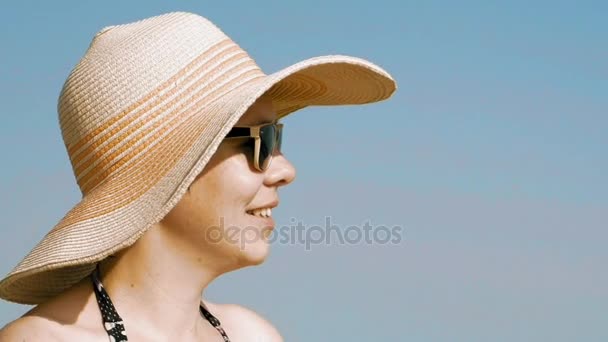 Donna in piedi sulla spiaggia con il suo cappello fantasia — Video Stock