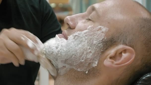 Um homem está sentado numa barbearia para ser preparado. — Vídeo de Stock